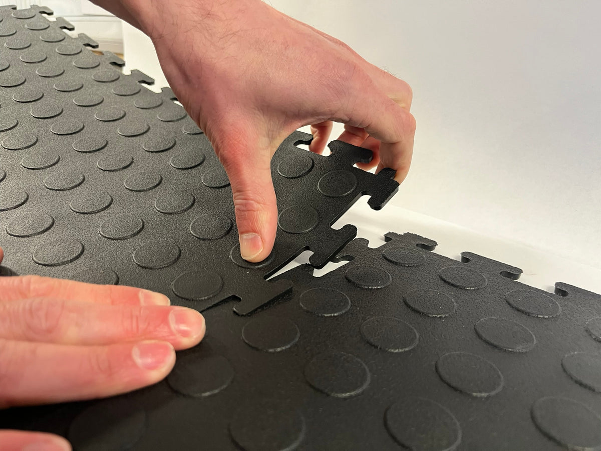 Hands joining the interlocking edges of two garage floor tiles, so easy to install